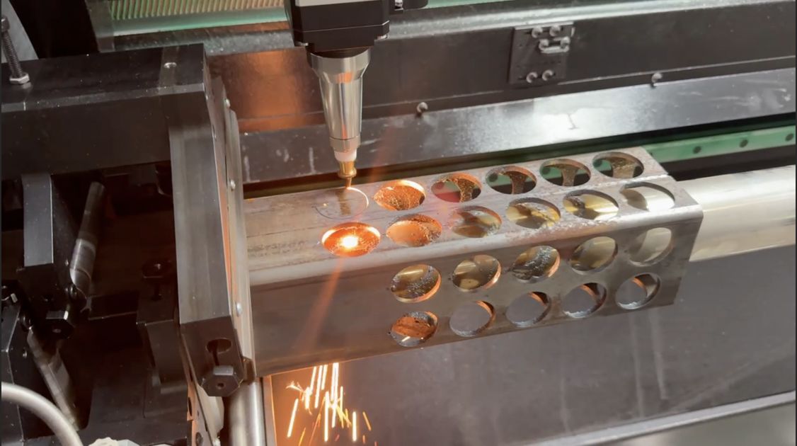 Tube laser cutting circular holes through a rectangular steel tube with sparks