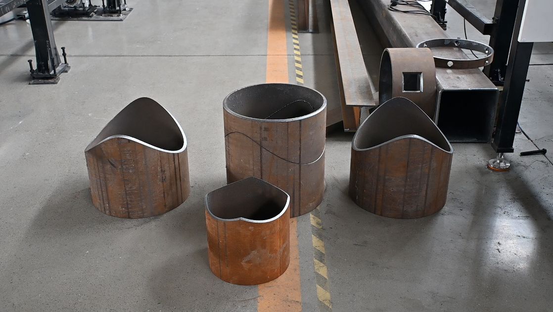 Unassembled laser-cut steel pipe components staged for welding