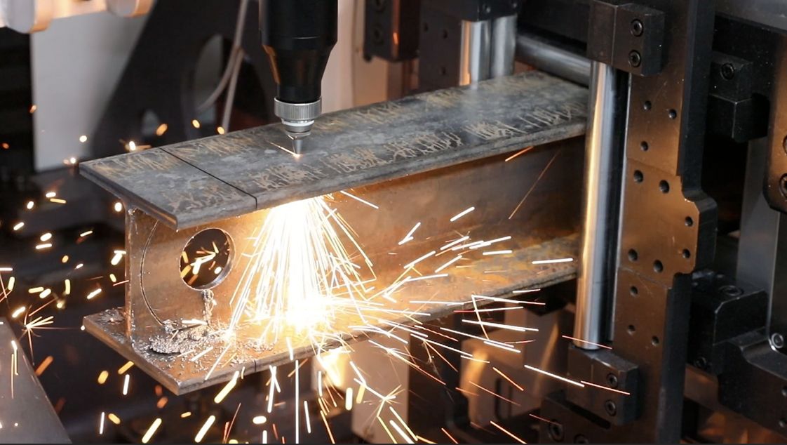 Tube laser cutting a structural steel H-beam with bright sparks at Industrial Machine Worx