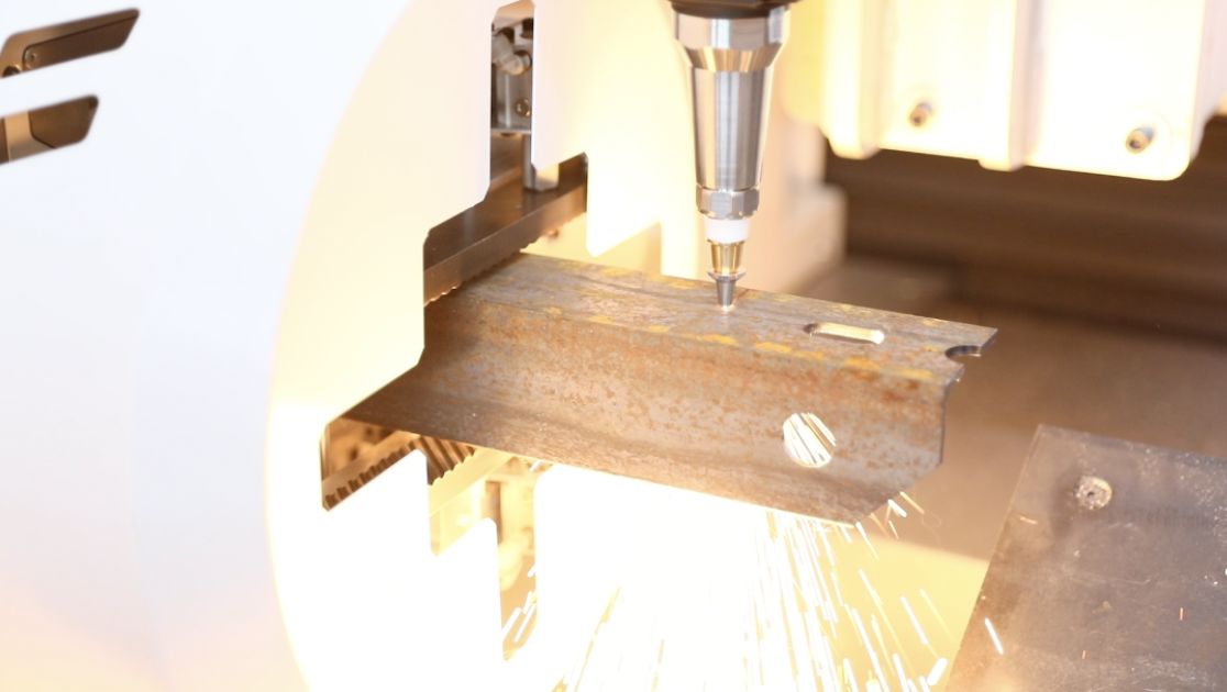Tube laser cutting an angled steel profile with a spray of sparks